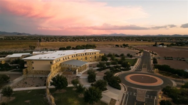 Aerial view of a city at sunset featuring a roundabout in front of a municipal complex.