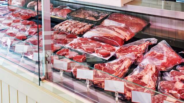 A display case filled with various types of packaged meats, including steaks and ground meats.