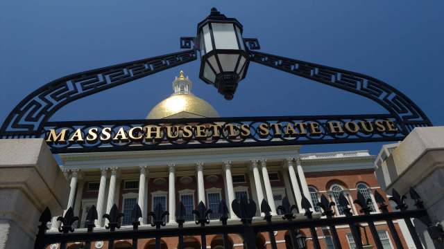 The Massachusetts State House entrance, featuring an ornate black gate with gold lettering.