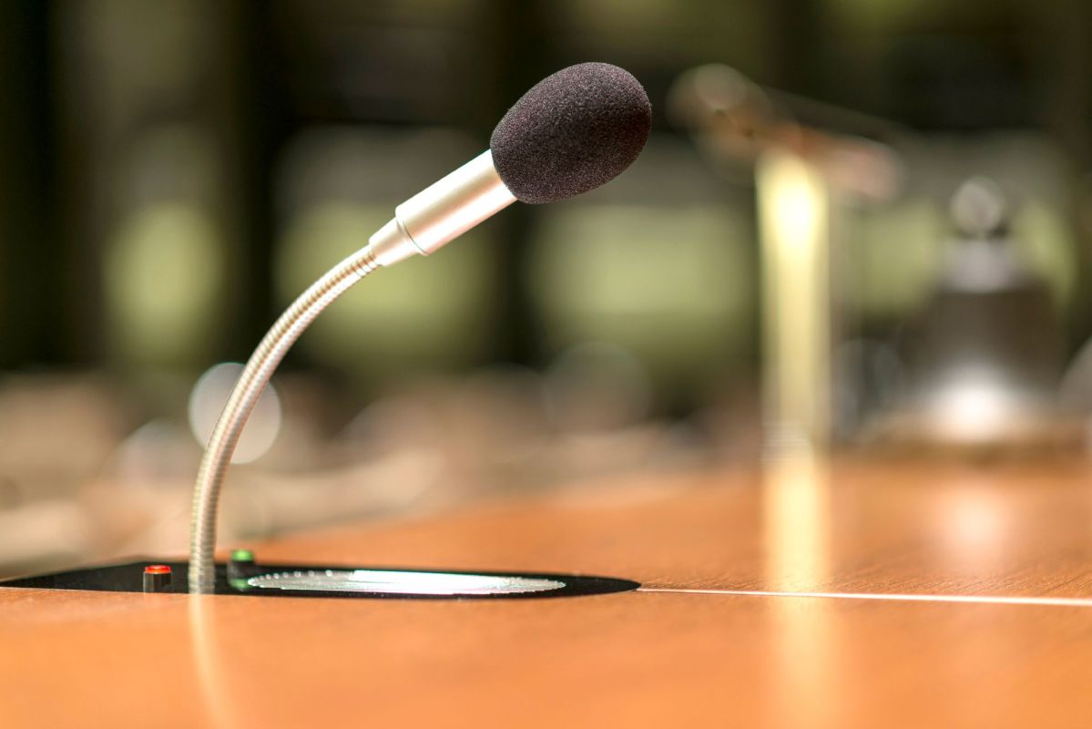 A microphone on a wooden conference table with a blurred background.