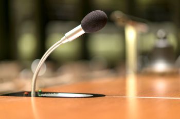 A microphone on a wooden conference table with a blurred background.