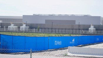 A construction site with a blue fence featuring the Meta logo.