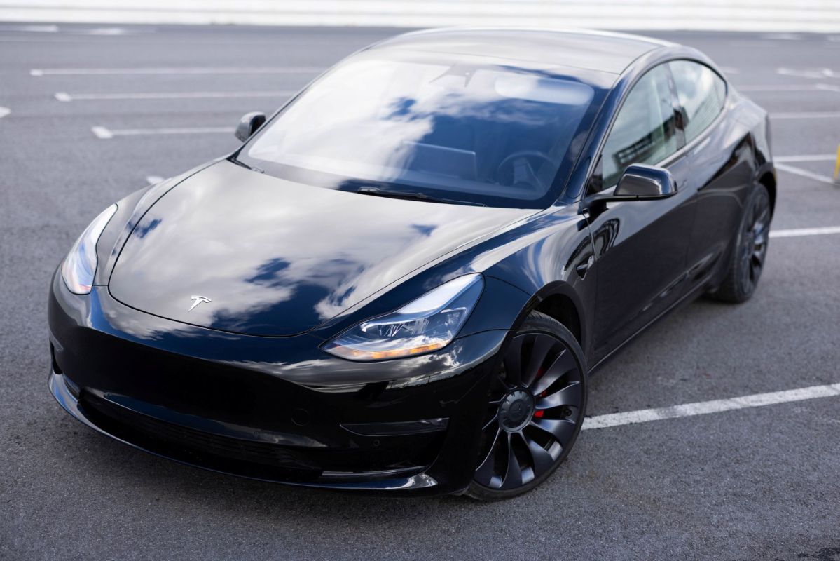 A black Tesla Model 3 in a parking lot.