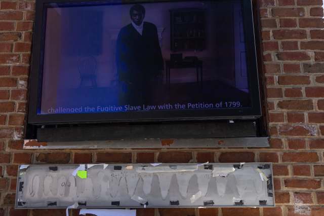 A digital display on brick wall with information about the Fugitive Slave Law.