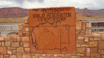 A stone sign marking the entrance to the Navajo Reservation, displaying a map of the area and states.