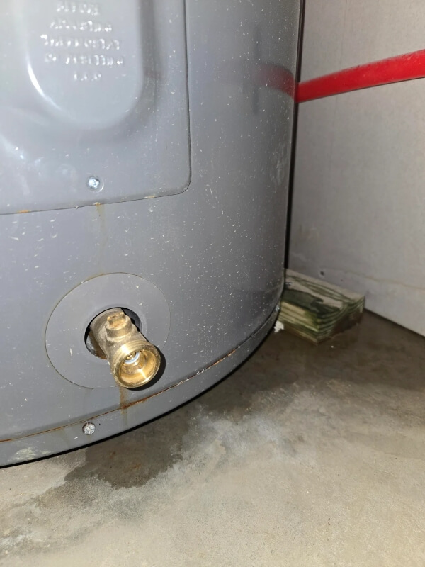 A water heater leaking moisture onto the floor. 