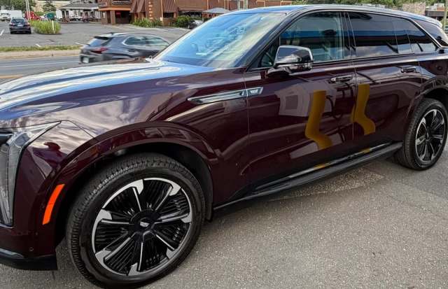 A maroon SUV with sleek black rims parked on a street with blurred vehicles in the background.