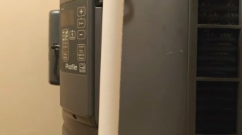A gray appliance control panel beside a beige wall.
