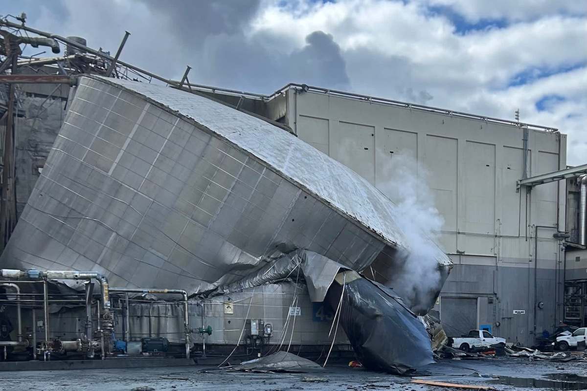 A collapsed section of an industrial building with smoke billowing.
