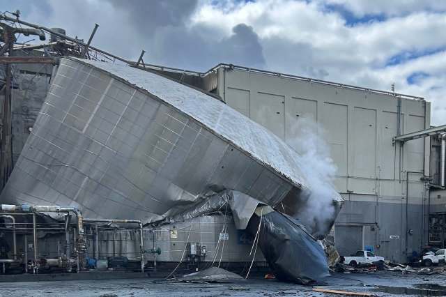 A collapsed section of an industrial building with smoke billowing.