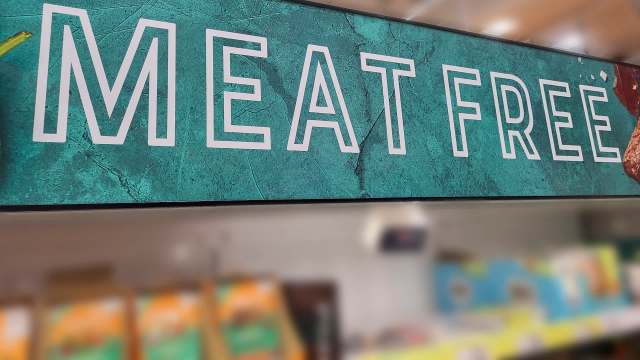 A sign reading "Meat Free" in a grocery store.