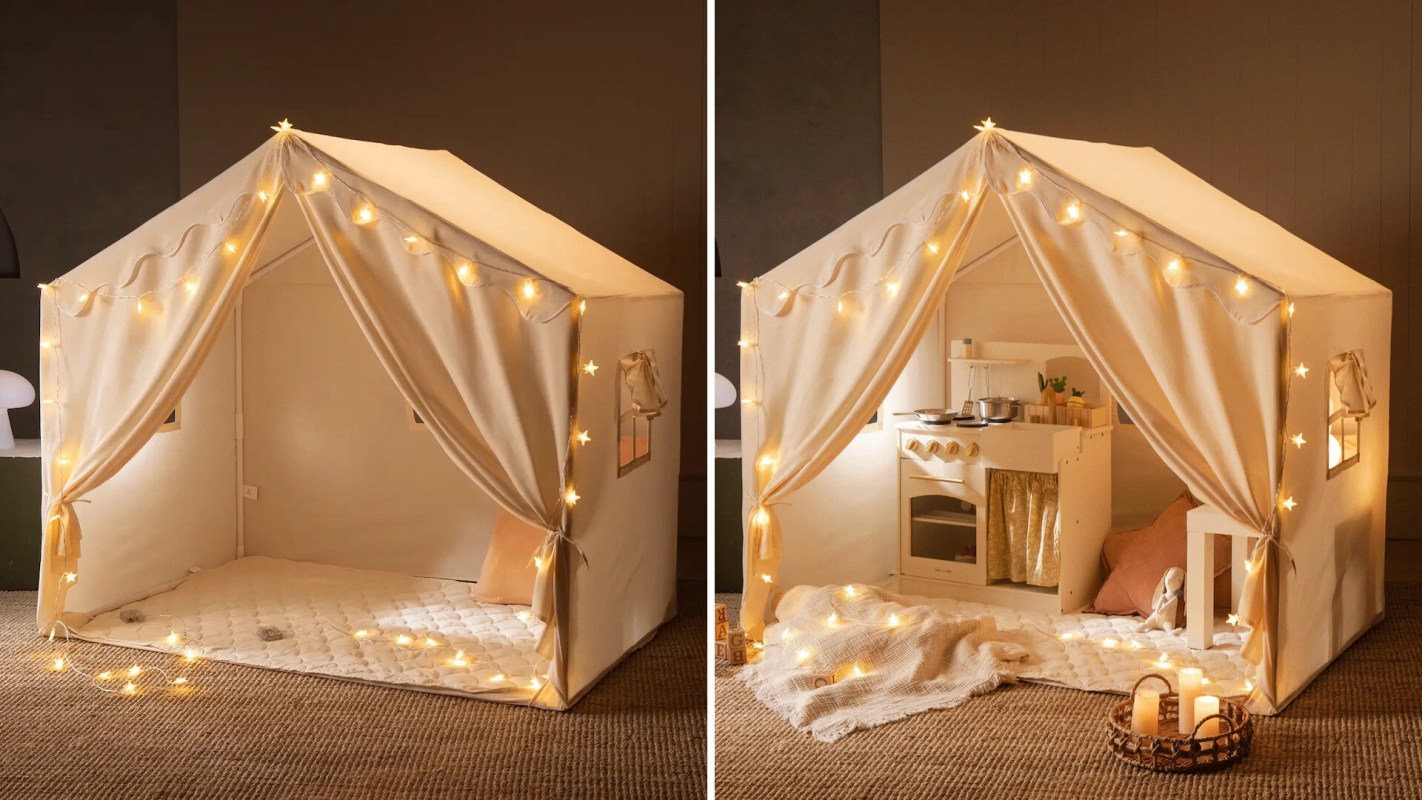 A children's tent with fairy lights, featuring a play kitchen inside and a quilted floor mat.