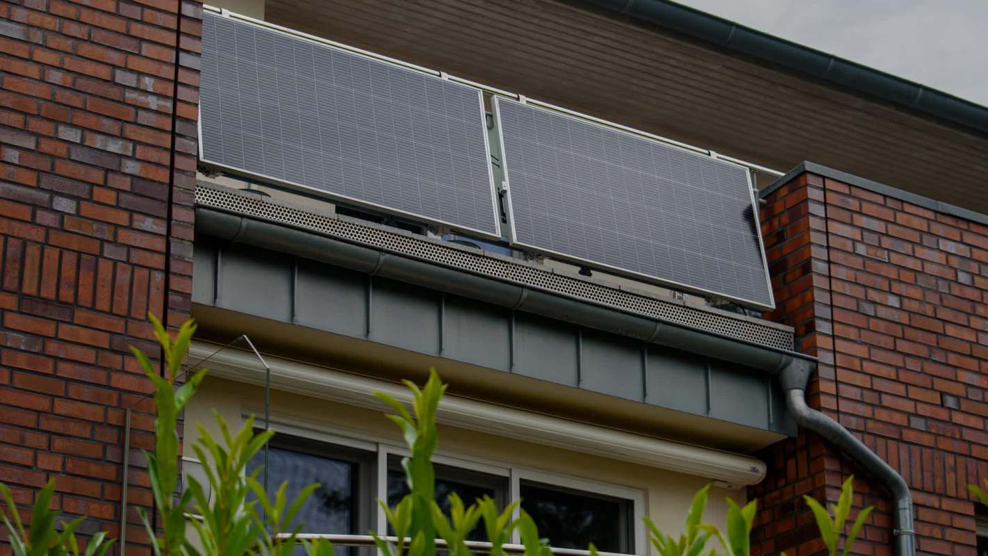 Two solar panels mounted on a balcony of a brick building.