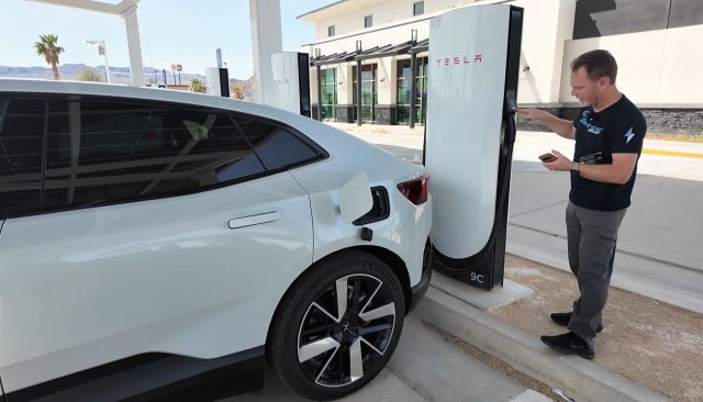 A person charging a Polestar 4 at a Tesla charging station.