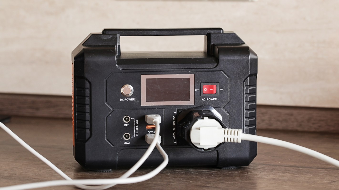 A portable power station with multiple ports and a digital display, connected to a power source.
