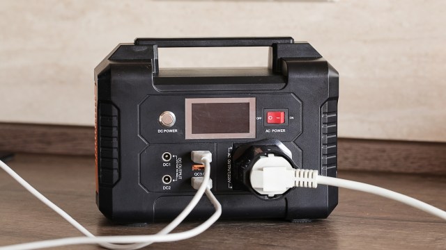 A portable power station with multiple ports and a digital display, connected to a power source.