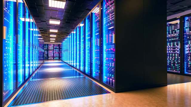 A brightly lit server room lined with blue illuminated racks of servers and a metallic grating floor.