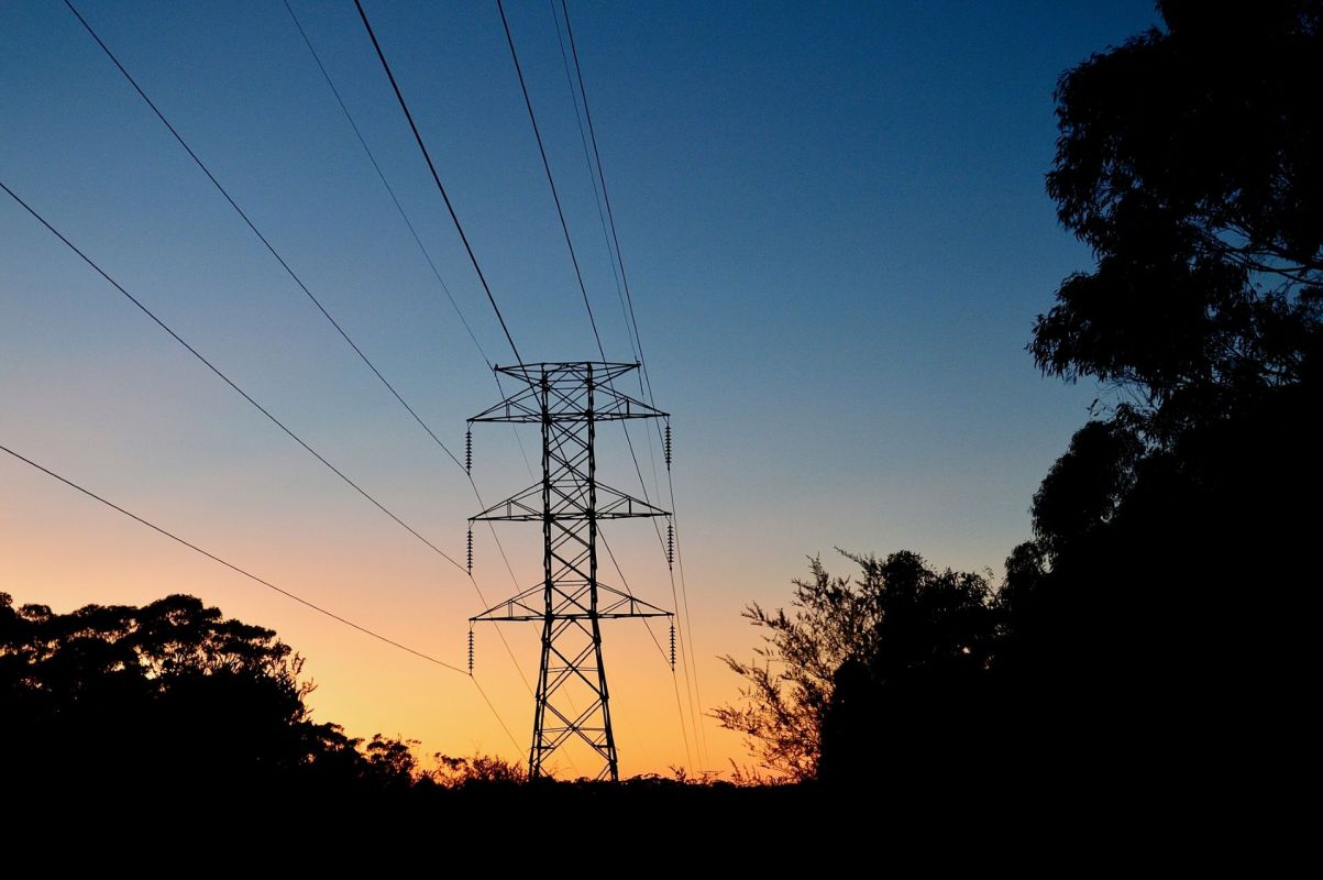 The silhouette of a transmission tower at sunset.
