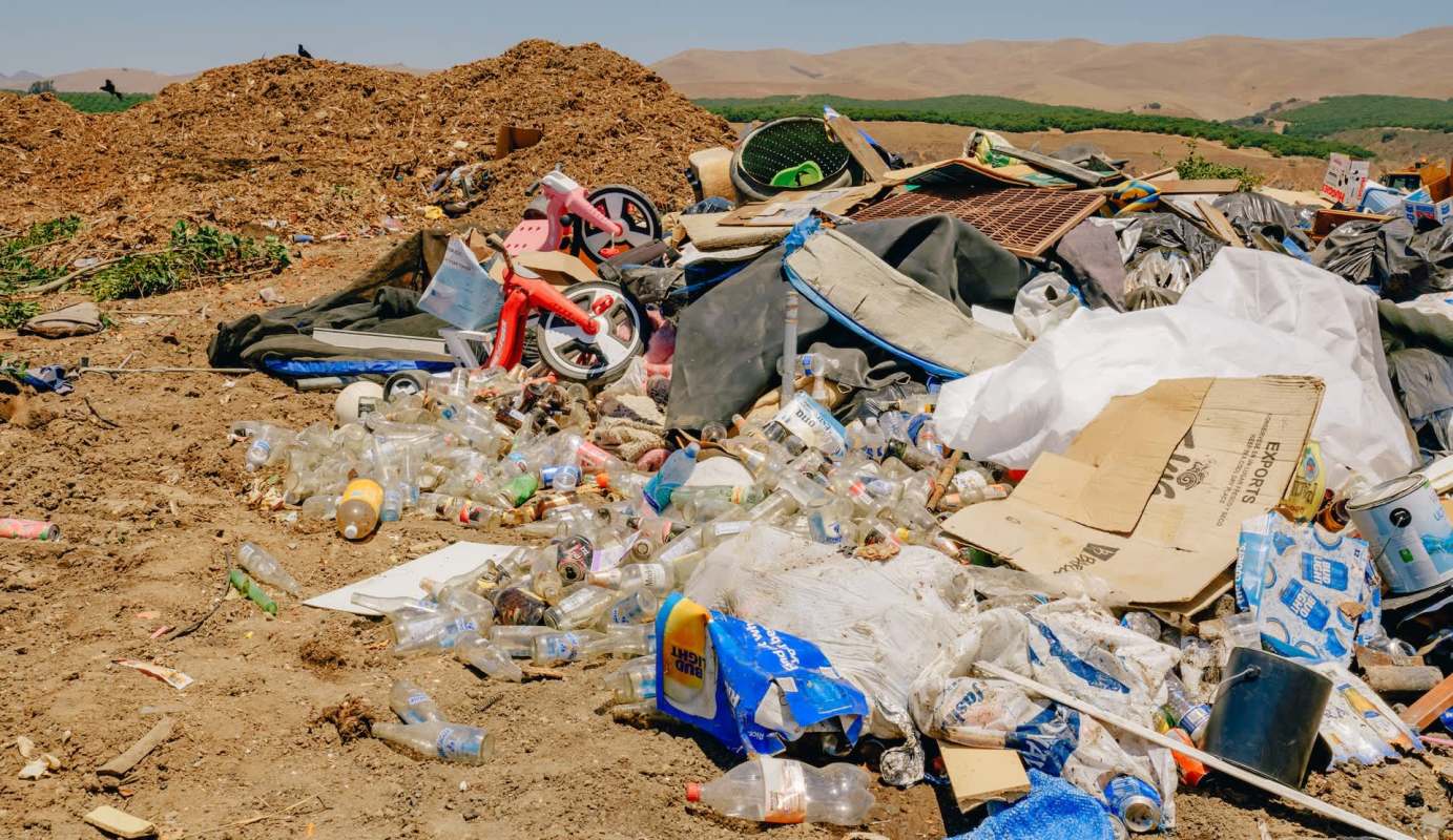 A landfill strewn with plastic bottles, cardboard, toys, and debris.