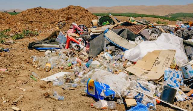 A landfill strewn with plastic bottles, cardboard, toys, and debris.