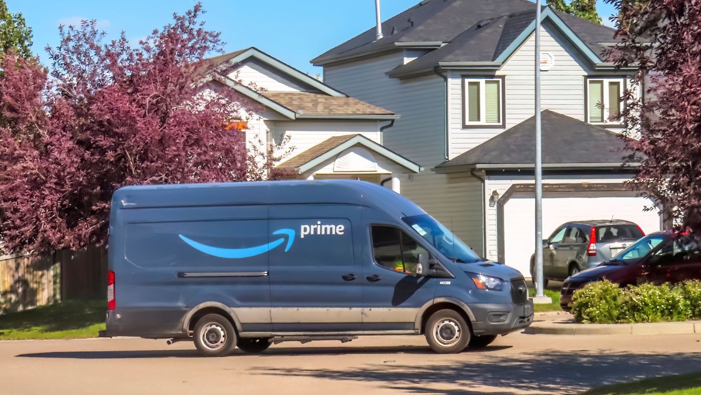 An Amazon Prime delivery van driving through a residential neighborhood.