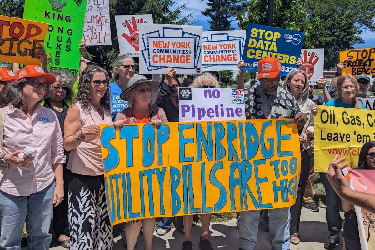 A group of protesters holding signs advocating against utility costs and environmental issues.