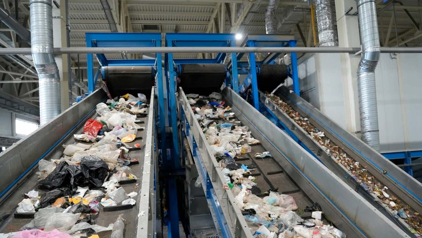 Conveyor belts transporting mixed waste at a recycling facility.