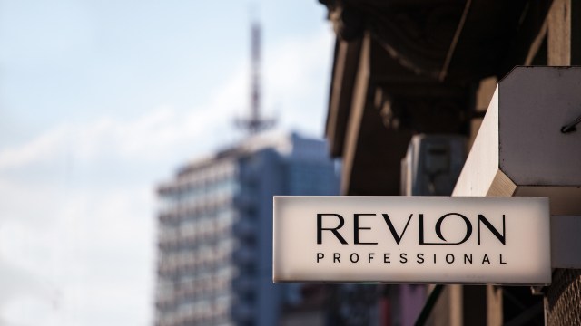 A close-up of a sign displaying "REVLON PROFESSIONAL" against a cityscape background.