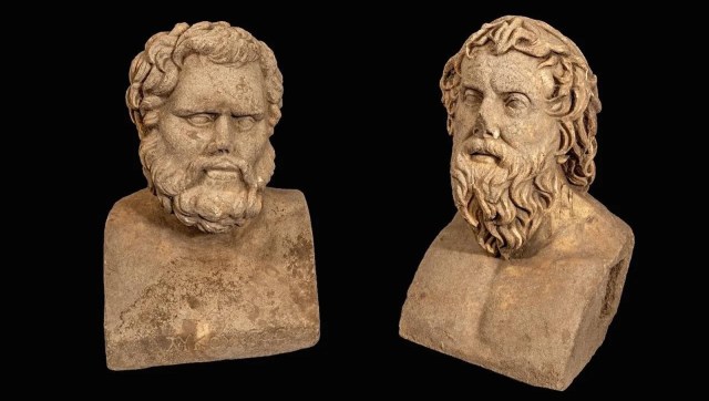 Two ancient stone busts of bearded men, depicting classical Roman sculptural style against a black background.