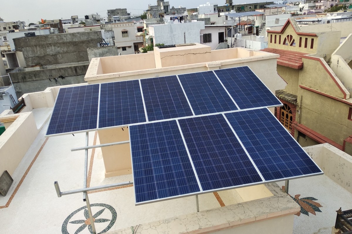 A solar panel installation on a rooftop overlooking a residential area with buildings in the background.
