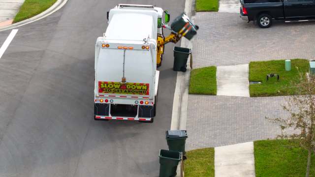 A garbage truck lifting a bin on a residential street.