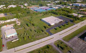 An aerial view of a commercial area with green fields, parking lots, and storage units in the background.