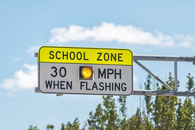 A traffic sign indicating a school zone with a speed limit of 30 MPH when the light is flashing.