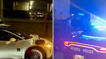 A self-driving Waymo vehicle with an Uber decal is stopped in front of an Atlanta Police car with flashing lights at night.