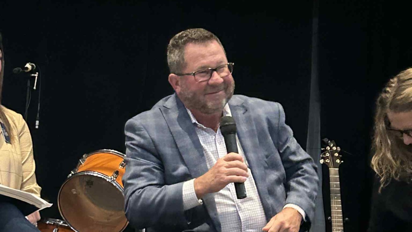 Shelbyville Mayor Scott Furgeson smiles while holding a microphone during a discussion event.