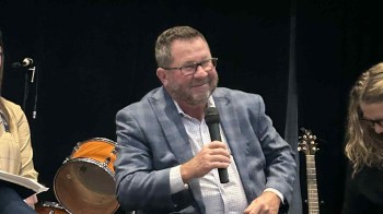 Shelbyville Mayor Scott Furgeson smiles while holding a microphone during a discussion event.