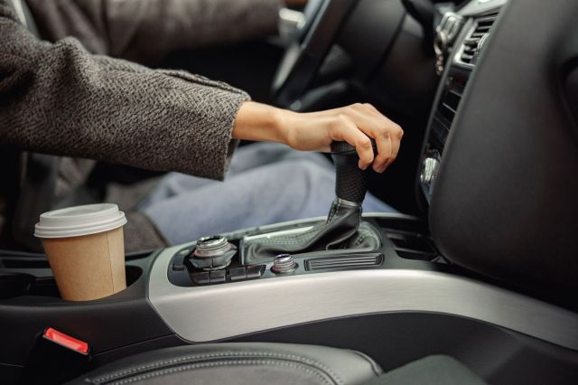 A person shifts the gear in a car.