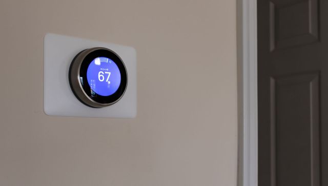 A smart thermostat displaying a temperature of 67 degrees Fahrenheit.