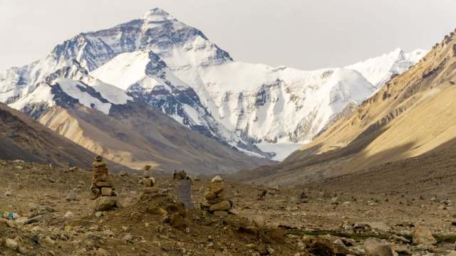 A rocky landscape with stacked stones in the foreground and Mount Everest in the background.