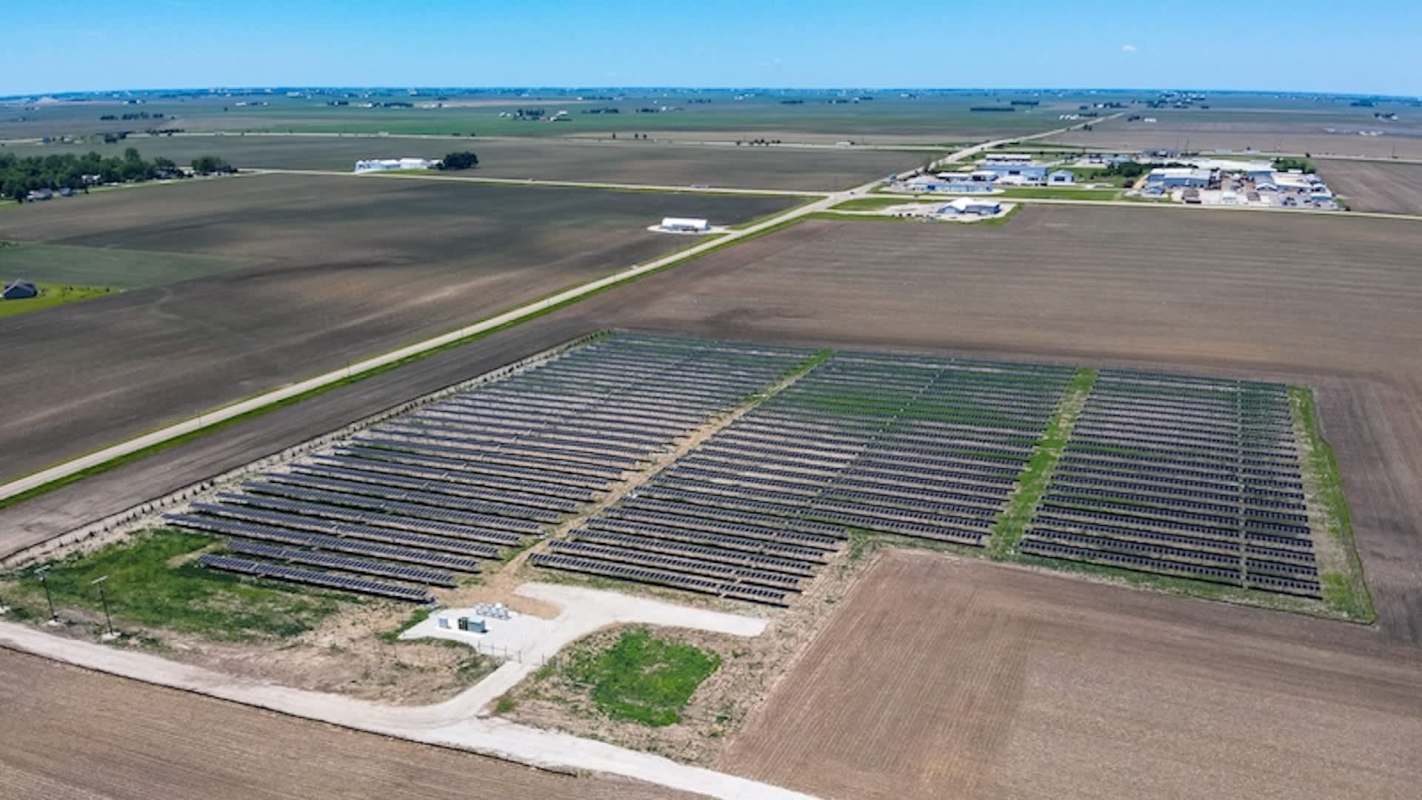 An aerial view of a large solar farm surrounded by farmland and a rural area.