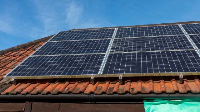 Solar panels installed on a tiled roof under a clear blue sky.