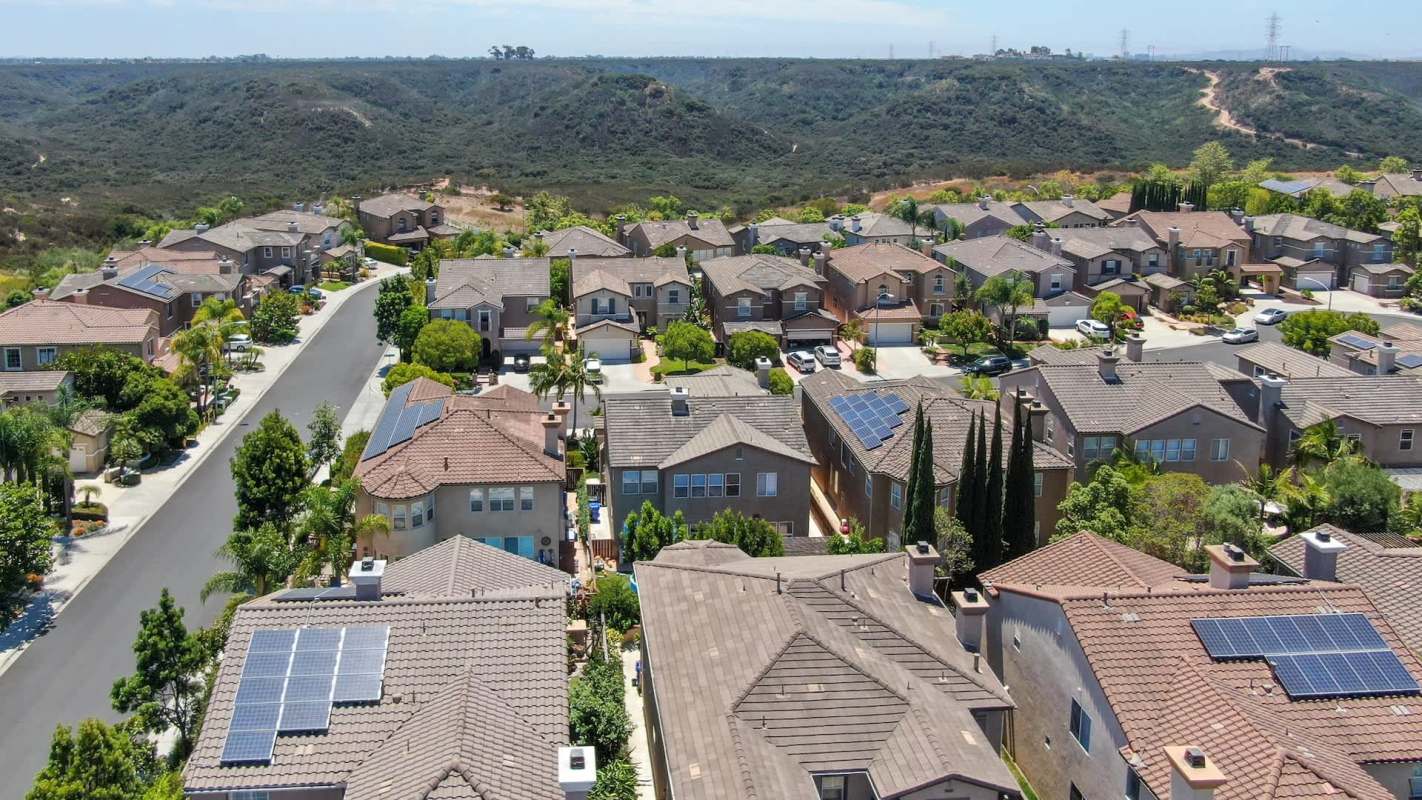 An aerial view of a suburban neighborhood, including houses with solar panels.