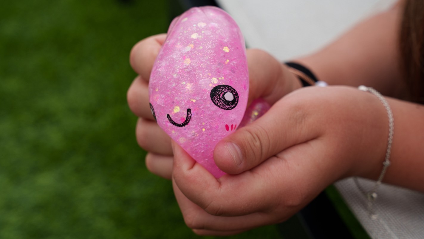 A child holds a sparkly pink toy shaped like a smiling octopus.