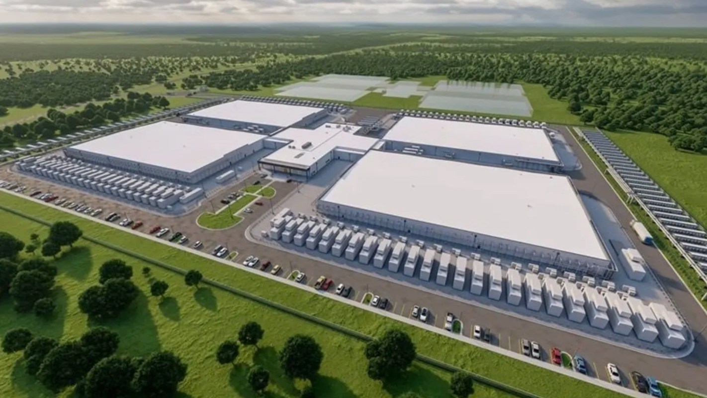 Aerial view of a large industrial facility with multiple buildings and parked vehicles in a green landscape.