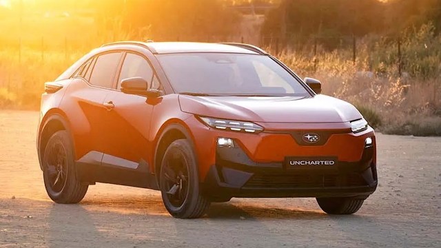 A red Subaru SUV with a sleek design is parked on a dusty road during sunset.