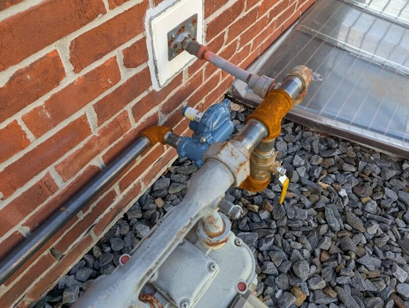 An unpainted natural gas line pressed directly against a masonry wall.
