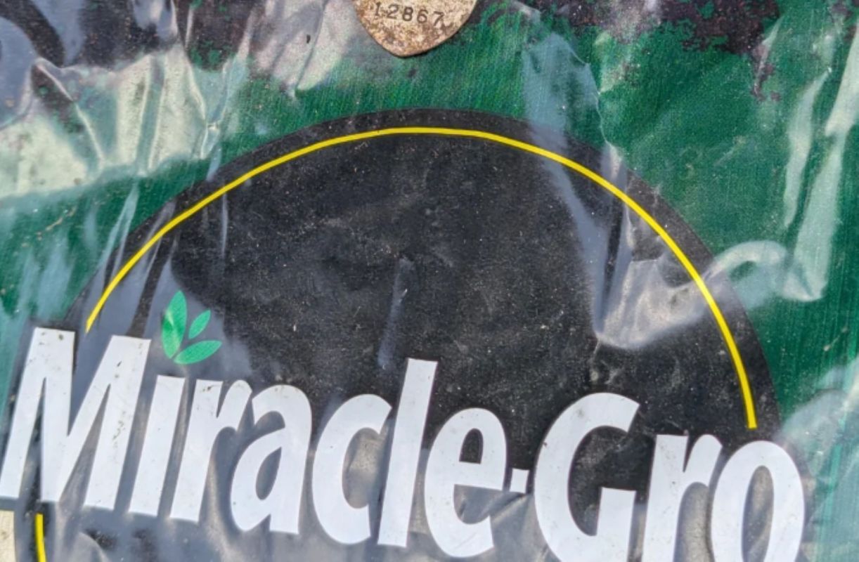 A Miracle-Gro fertilizer bag with a partially visible product label and dirt.