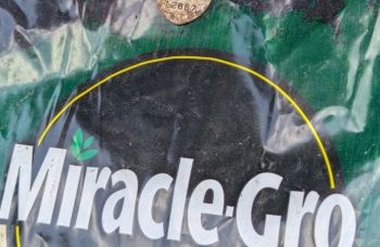 A Miracle-Gro fertilizer bag with a partially visible product label and dirt.