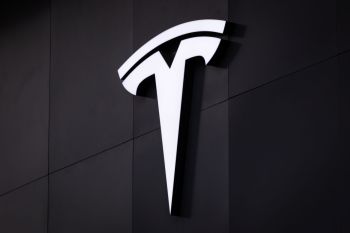 A white Tesla logo on a black background.