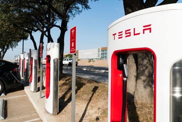 A row of Tesla charging stations in a parking lot.